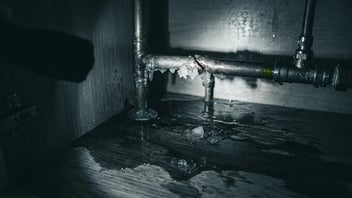 Corroded cast iron drain section and water staining — warning signs of pipe failure and related water damage.