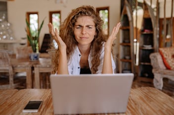 A woman looks frustrated at her laptop after hearing her insurance claim has been denied