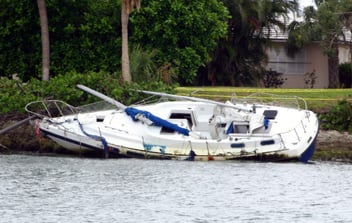 A capsized boat at a dock, completely destroyed by a recent storm