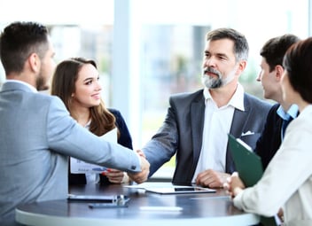 A homeowner and public adjuster shake hands in a meeting