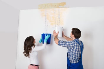 A couple tries to stop rain water entering in from a roof leak