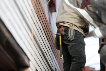 A homeowner attempts to repair the siding on his home