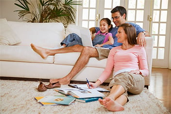 A family reclines on the couch completing paper work