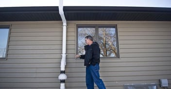 A man inspects the outside of the home for possible radon contamination