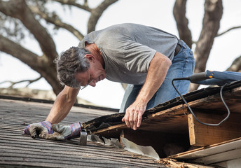 A roofer repairs roof damage after a Florida storm