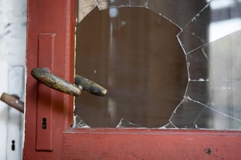 A smashed window next to a door handle, indicating a robbery