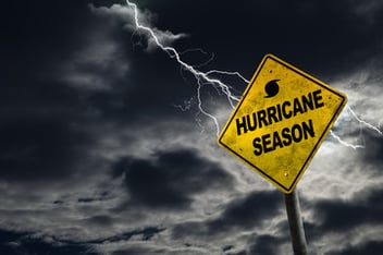 A sign that warns of hurricane season, with lightning and dark clouds in the background