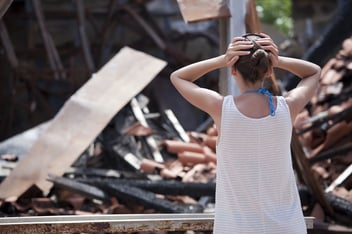 A woman looks on in shock after her property is destroyed