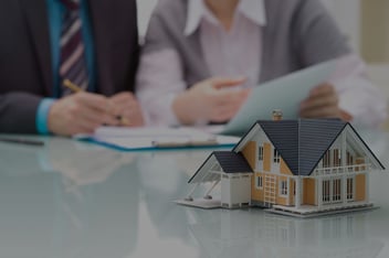 An image of public adjusters preparing a claim in front of a model home.