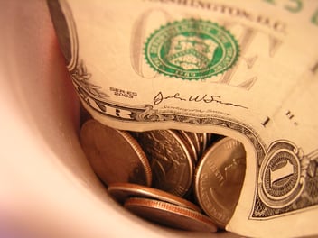 A cup full of coins and single dollar bills, representing the better return you could receive if you reopen your claim