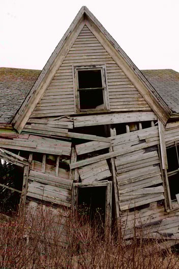 A heavily damaged home, with broken walls and caved in roof.